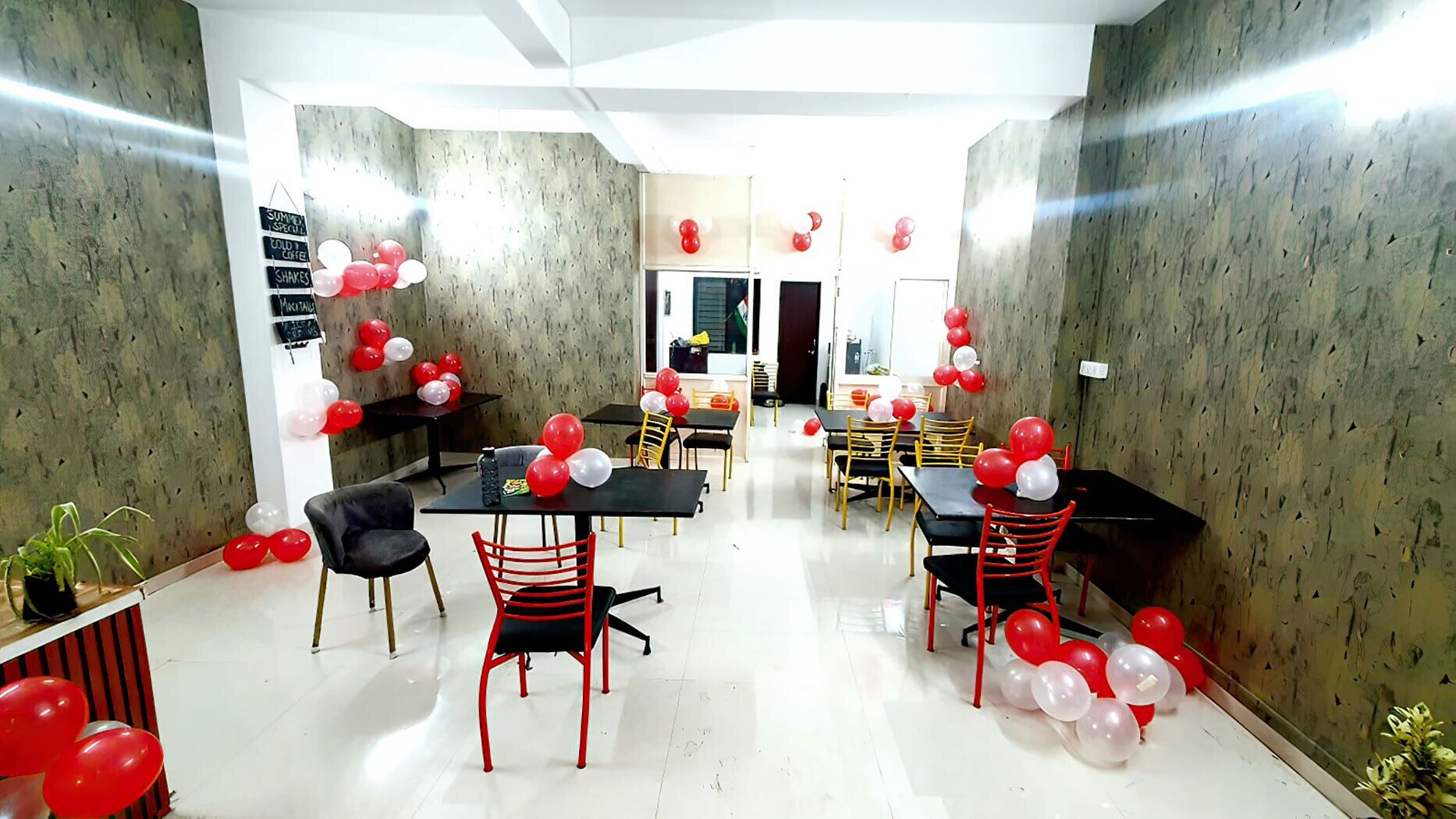 A dining area with tables and chairs, balloons, and a menu board.