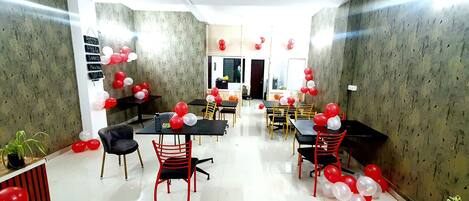 A dining area with tables and chairs, balloons, and a menu board.