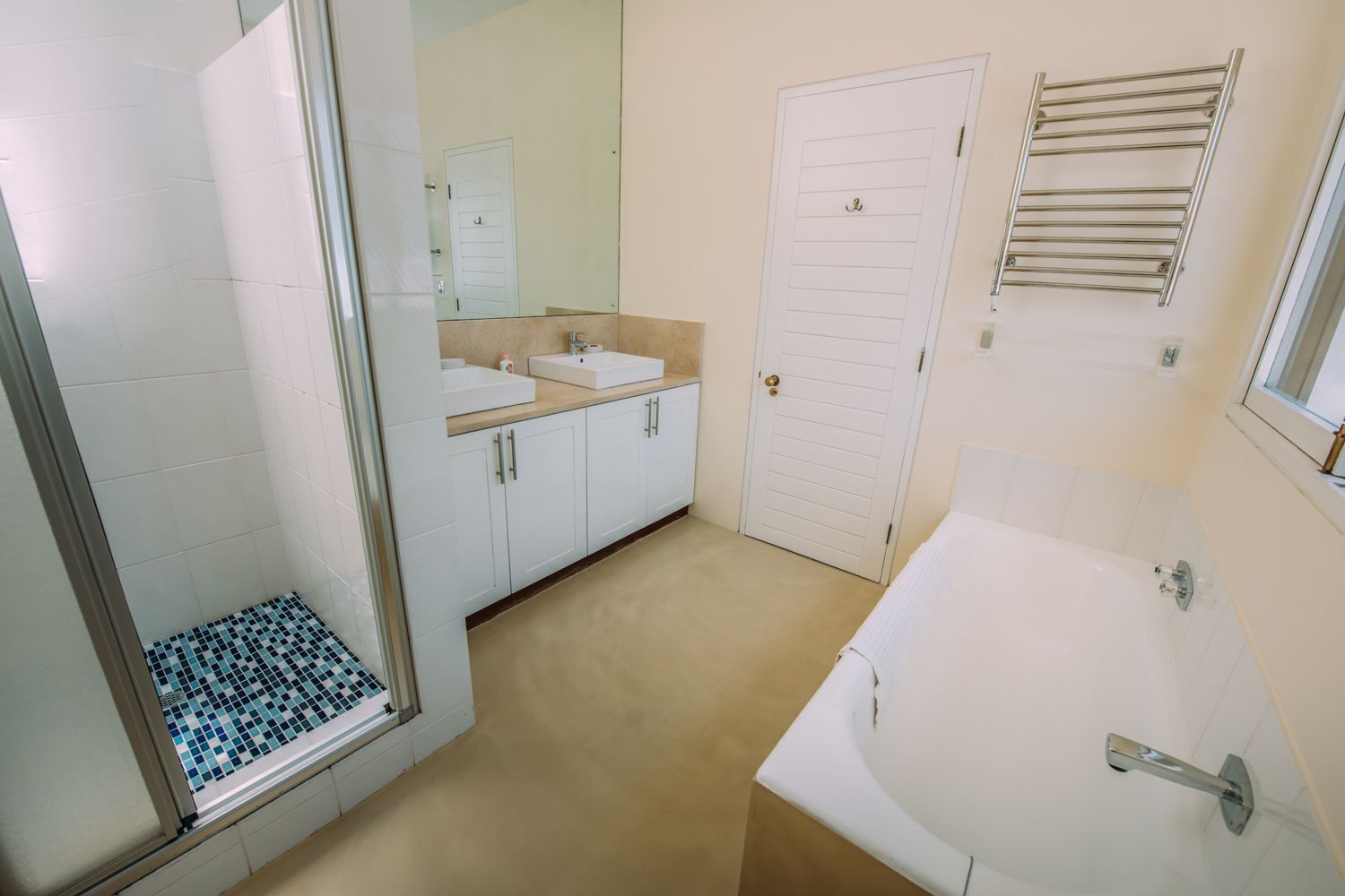 Un baño con ducha, dos lavamanos, inodoro y bañera.