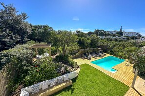 A backyard with a swimming pool, wooden deck, and a pergola. - Villa Rothersand - Three Bedroom Villa, Sleeps 6 (Plettenberg Bay)