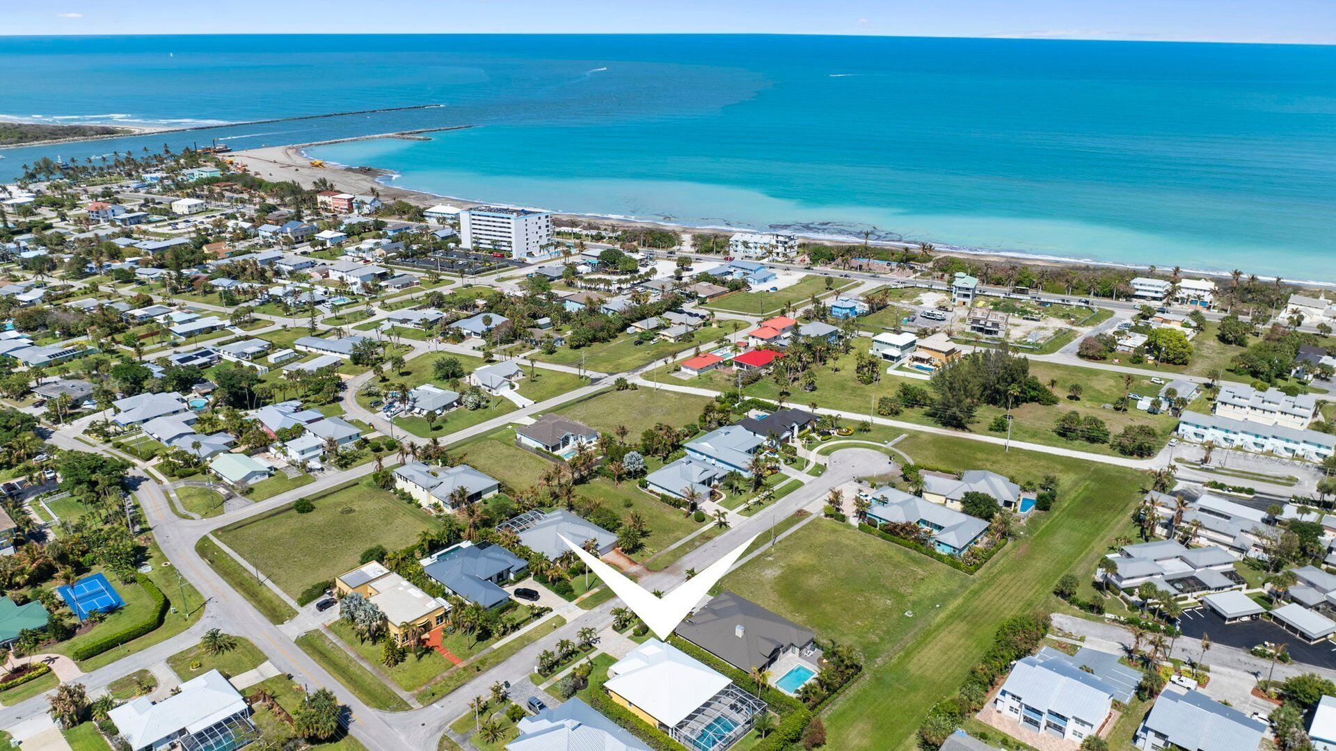 Luftaufnahme einer Küstenwohngegend mit Häusern, Straßen und einem Strand.