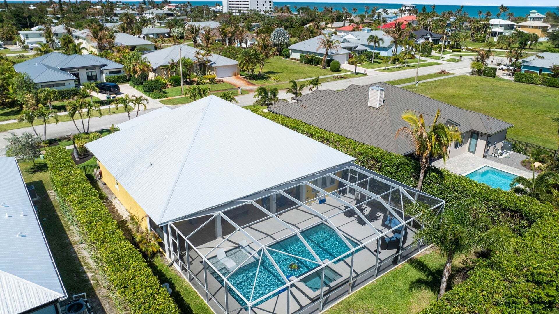 A large house with a swimming pool, surrounded by lush greenery and a view of the ocean.
