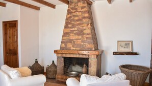 A cozy living room with a stone fireplace, white furniture, and rustic decor.