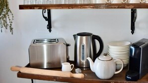 A kitchen shelf with various kitchenware, including a toaster, a kettle, and a pot.