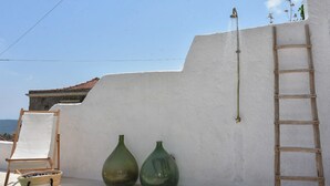 A white wall with a ladder and two green vases against it.
