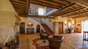 A spacious lobby with a grand staircase, a fireplace, and a large mirror.