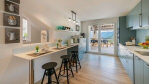 A modern kitchen with a central island, bar stools, and a view to the outside.