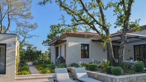 A modern house with a patio area featuring two lounge chairs and a stone wall. - Residence Anabelle - Four Bedroom Villa, Sleeps 8 (Tourrettes)