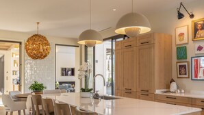 A modern kitchen with a large island, pendant lighting, wooden cabinets, and a dining area with chairs. - Residence Anabelle - Four Bedroom Villa, Sleeps 8 (Tourrettes)