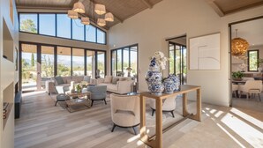 A spacious living area with a large window, a wooden ceiling, and a dining area with a table and chairs. - Residence Anabelle - Four Bedroom Villa, Sleeps 8 (Tourrettes)