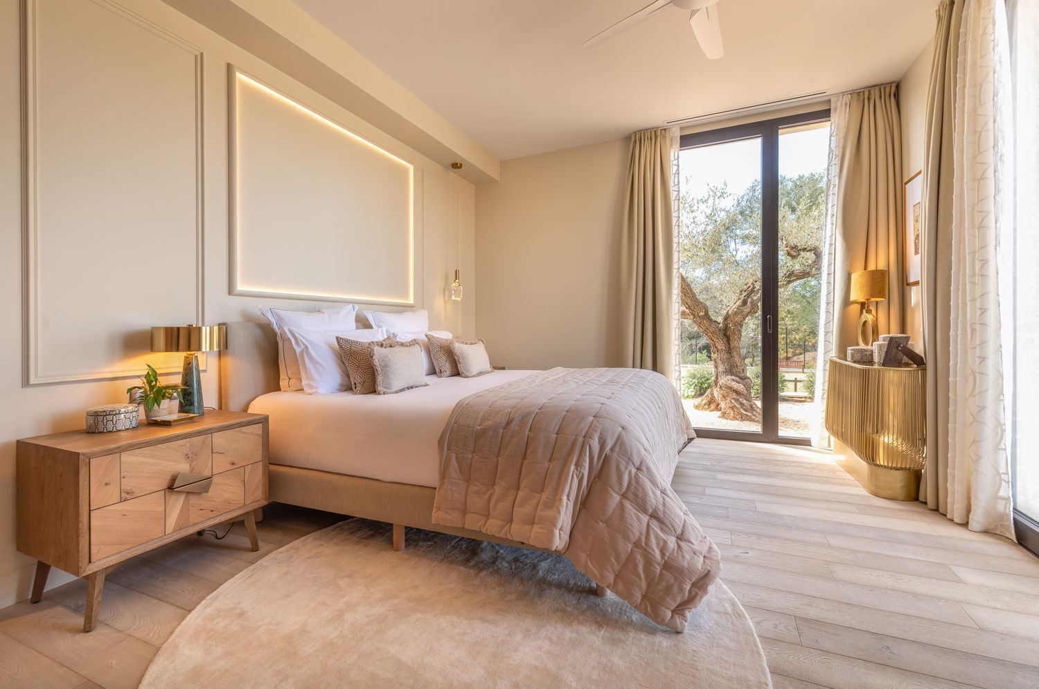 A modern bedroom with a large bed, bedside tables, a nightstand, and a view of the outdoors.