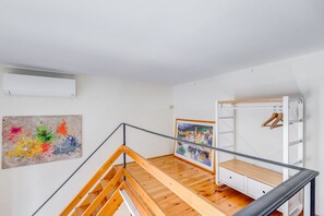 A modern interior with a wooden staircase, a white wall, and a painting.