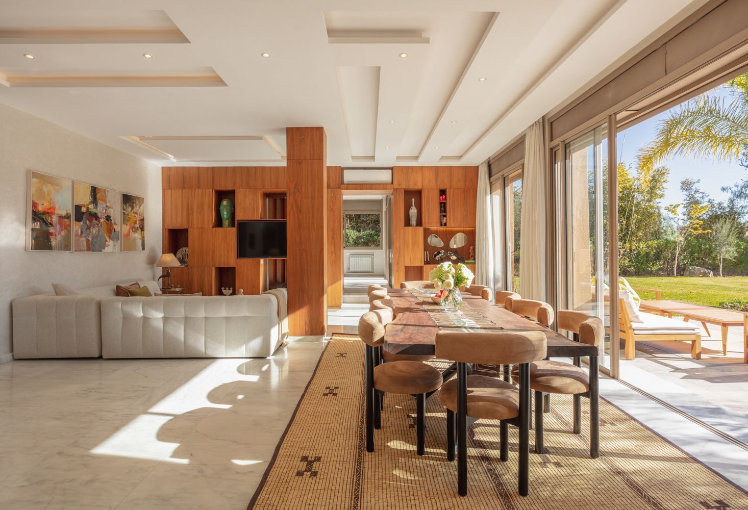 A modern interior with a dining area, a living room, and a large window offering a view of the outdoors.