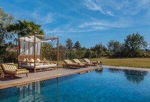 A pool area with lounge chairs, a canopy, and a clear blue sky.