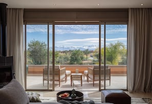 A spacious balcony with a view of mountains and greenery, furnished with a table and chairs.