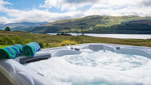 Un jacuzzi con vistas panorámicas a colinas y un lago.
