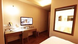 A hotel room with a bed, a desk, a chair, a television, and a window. - Kindness Hotel Qixian Kaohsiung (Kaohsiung)