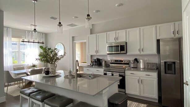 A modern kitchen with white cabinets, stainless steel appliances, and a central island with bar stools.