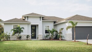 A modern two-story house with a grey exterior, a black front door, and a garage.
