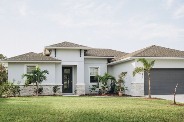 A modern two-story house with a grey exterior, a black front door, and a garage. - SPACIOUS family house, North Port with POOL/ SPA, SECLUDED (North Port)