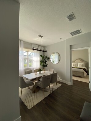 A modern dining area with a white table, grey chairs, and a large potted plant. - SPACIOUS family house, North Port with POOL/ SPA, SECLUDED (North Port)