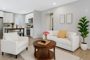A modern living room with a white sofa, a coffee table, and a potted plant. - Leyla| Pool/Spa|Downtown|Freeways|Beaches (San Diego)