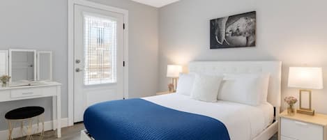 A bedroom with a bed, bedside tables, a desk, and a chair.