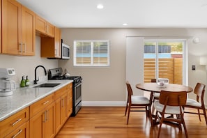 A kitchen with wooden cabinets, a stove, and a dining area with a table and chairs.