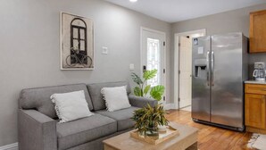 A living room with a grey sofa, a wooden coffee table, and a refrigerator.