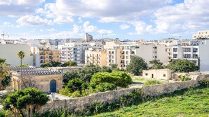 Zona residencial con edificios de varios pisos, un muro de piedra y vegetación.