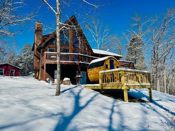 A log cabin with a large deck and a snow-covered landscape.