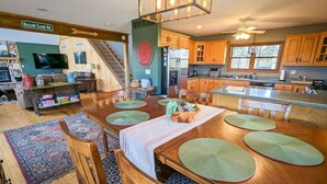 A spacious kitchen with wooden cabinets, a dining area with a large table and chairs, and a staircase leading to an upper level.