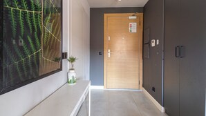 Ein Flur mit einer Holztür, einem Blumentopf und einer großen Farn-Kunst am Wand.