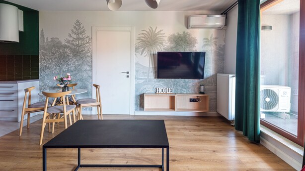 Ein modernes Wohnzimmer mit einem schwarzen Couchtisch, Holzstühlen, einem Fernseher und Wandgemälde.