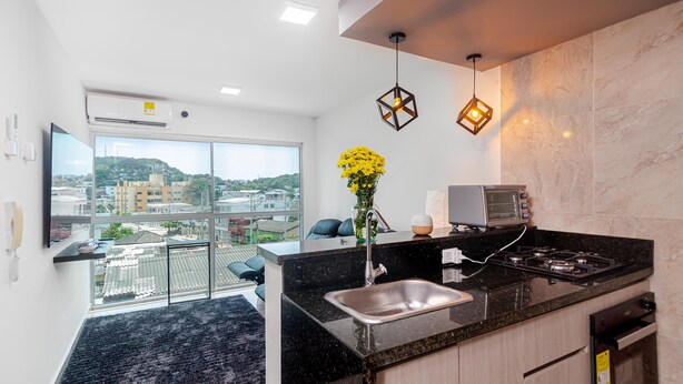 A modern kitchen with a large window, a black countertop, and a gas stove.