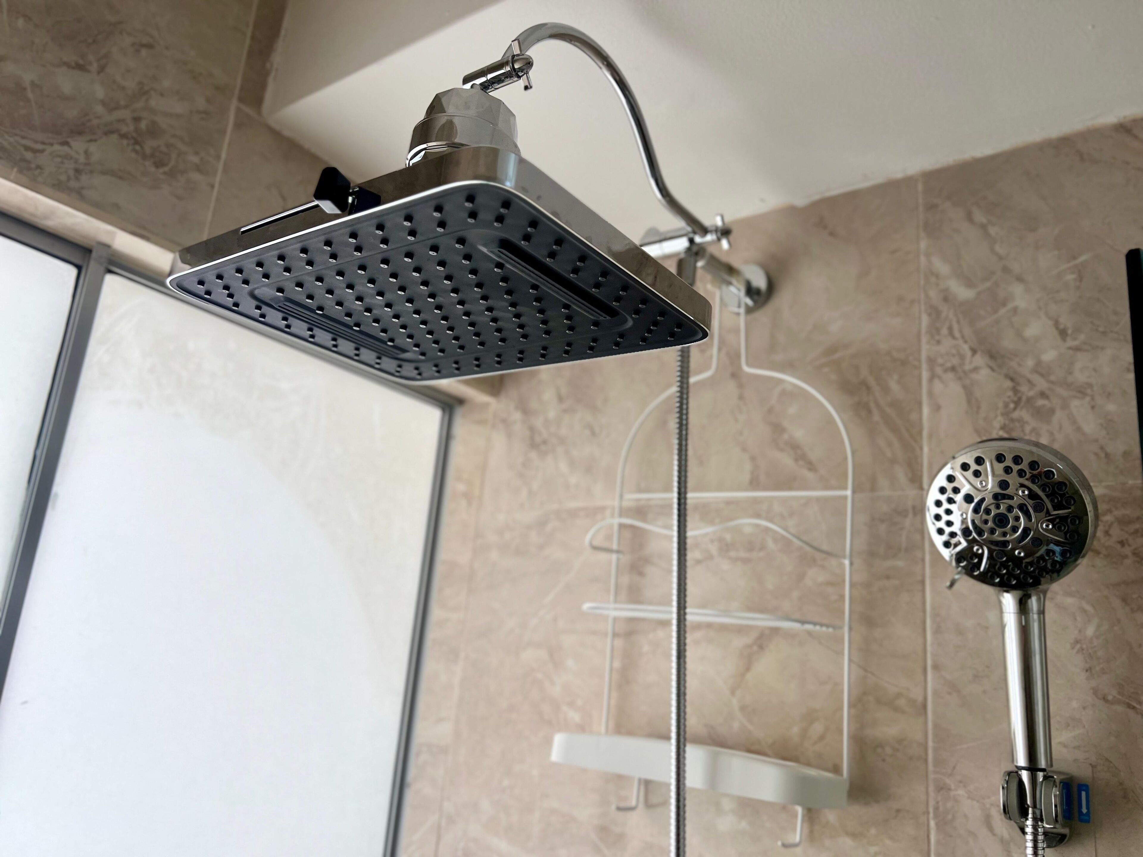 A shower with a square head, a handheld showerhead, and a wall-mounted faucet.
