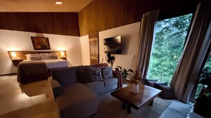 Una sala de estar moderna con un sofá, una mesita de centro, una cama y un televisor montado en la pared.