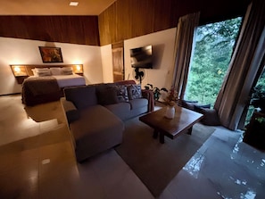 A modern living room with a sofa, a coffee table, a bed, and a TV mounted on the wall.