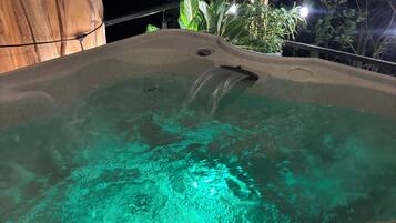 Uma banheira de hidromassagem com água cristalina, rodeada por árvores e uma estrutura de madeira.