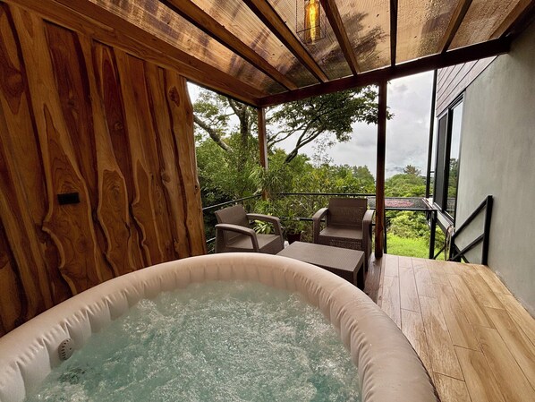 A hot tub in a wooden room with a view of greenery outside.