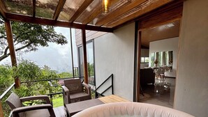 A hot tub with wicker chairs, a wooden deck, and a view of the outdoors.