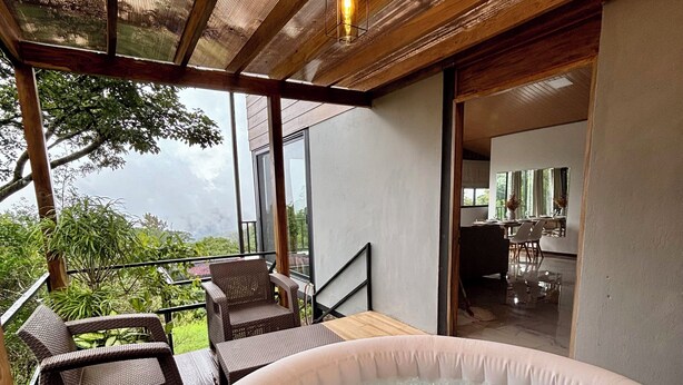 Un jacuzzi con sillas de mimbre, una terraza de madera y vistas al exterior.