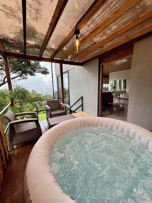 A hot tub with wicker chairs, a wooden deck, and a view of the outdoors.