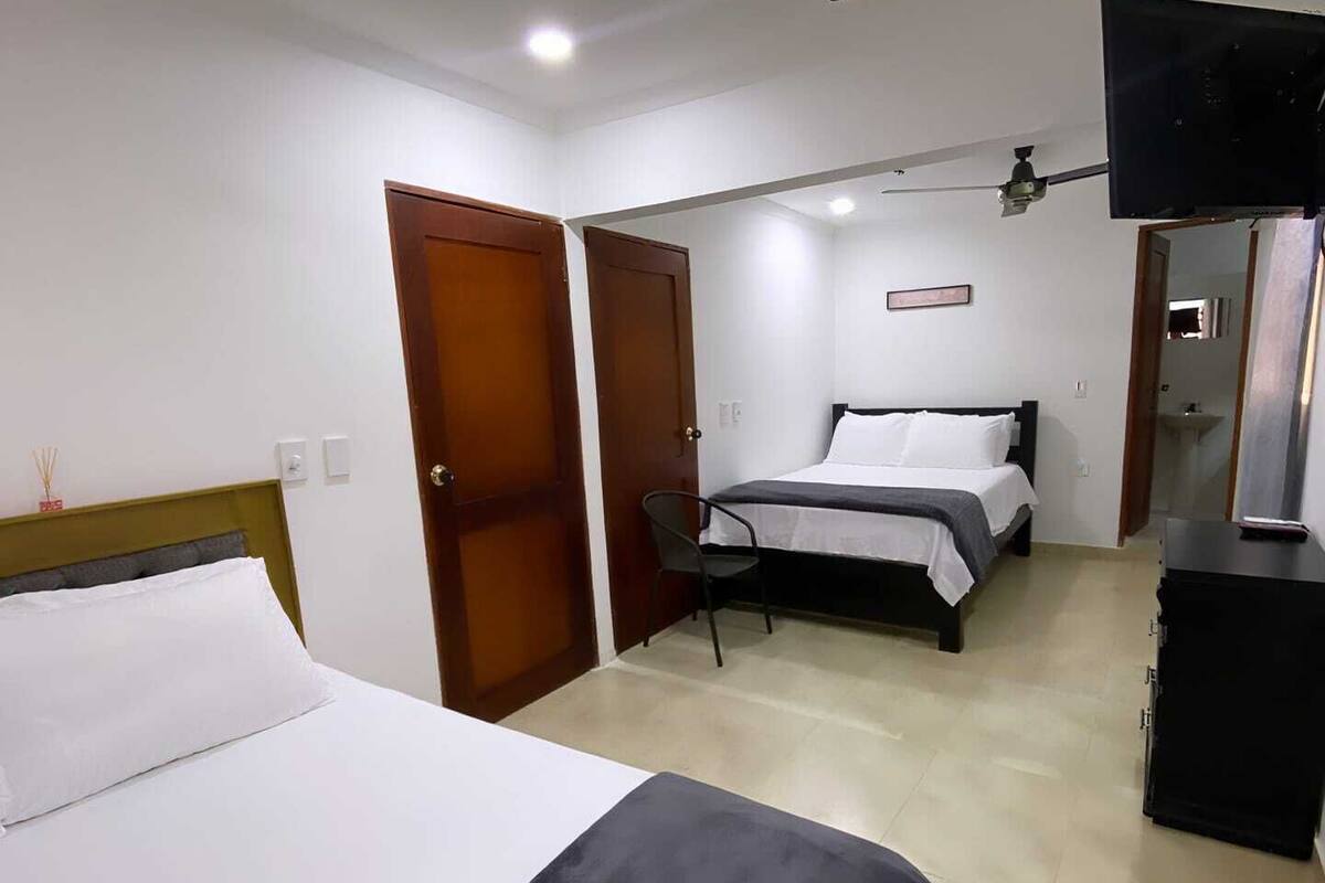 Een hotelkamer met een bed, een bureau, een stoel, een televisie en een kledingkast.