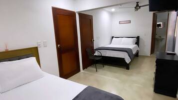 A hotel room with a bed, a desk, a chair, a TV, and a wardrobe.