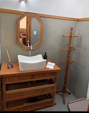 A bathroom with a wooden vanity, a white sink, a mirror, and a bamboo towel rack. - Linda casa em Boiçucanga (Sao Sebastiao)