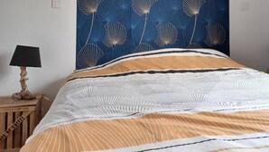 Une chambre à coucher avec un lit, une tapisserie murale et deux lampes fixées au mur.