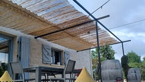 Un espace extérieur aménagé avec une table et des chaises, une pergola et des vases décoratifs.