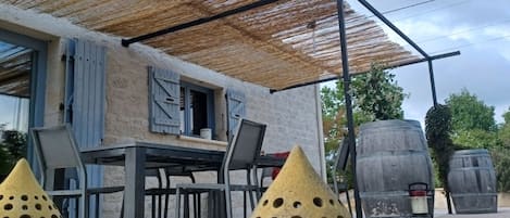 Área externa com mesa e cadeiras, uma pérgula e vasos decorativos.