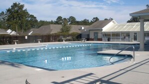 A swimming pool with a deck area, a covered seating area, and a lifeguard stand.